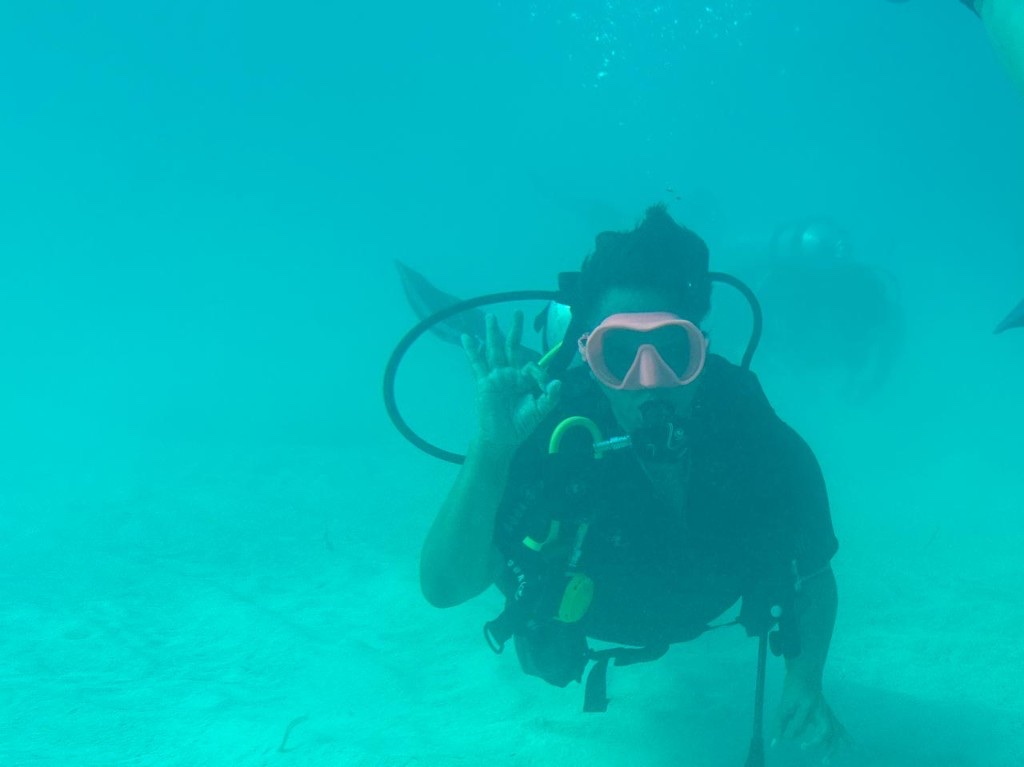 Scuba diving underwater, giving an OK hand signal